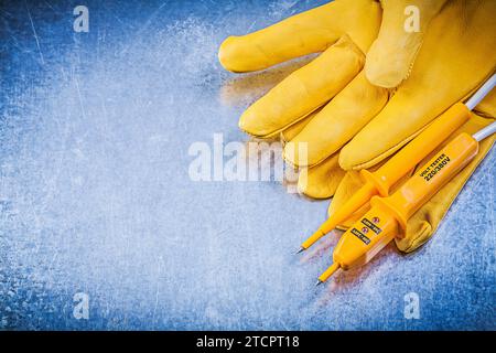 Gelbes elektrisches Prüfgerät Sicherheitshandschuhe auf verkratztem metallischem Hintergrund Elektrizitätskonzept Stockfoto