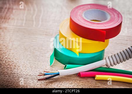 Horizontale Ansicht des Elektrokabels in Wellrohrrollen mit Isolierband Schrumpfschlauch auf Holzplatte Stockfoto