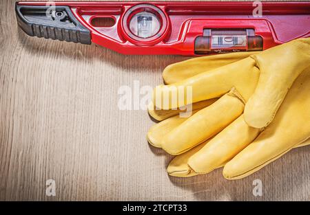 Gelbe Handschuhe und rote Wasserwaage auf Holzplatte Stockfoto