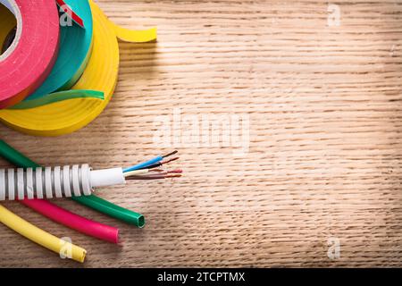 Luftaufnahme des Elektrokabels in Wellrohrrollen mit Isolierband-Schrumpfschlauch auf Holzplatte Stockfoto