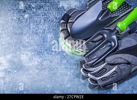 Gartenschutzhandschuhe Knieschutz Handschaufelkelle Gabel auf metallischem Hintergrund Landwirtschaftskonzept Stockfoto