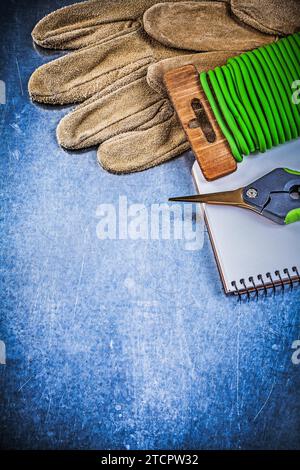 Gartenbinderdraht Gartenschere Schutzhandschuhe Arbeitsmappe auf metallischem Hintergrund Stockfoto