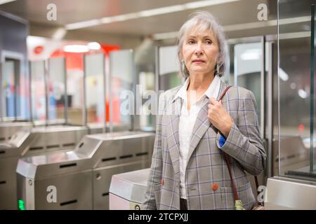 Reife Dame geht durch die Schranken in der U-Bahn-Station Stockfoto