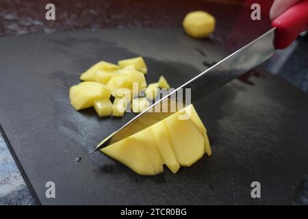 Zubereitung einer Kressensuppe, Schneiden roher Kartoffeln, Schneidebrett, Küchenmesser, Zerkleinern, schwäbische Küche, deftige Suppe, vegetarisch, gesund Stockfoto