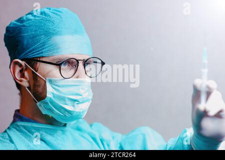 Junge männliche Chirurgin Arzt in Uniform mit einer Spritze bereitet sich auf die Injektion vor Stockfoto