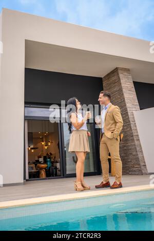 Vertikales Foto eines entspannten Paares, das feiert, dass sie ein Luxushaus gekauft haben Stockfoto