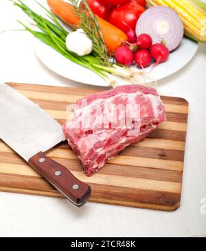 Hacken von frischen Schweineribs mit Gemüse und Kräutern, die fertig zum Kochen sind Stockfoto
