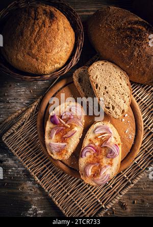 Blick von oben auf Brot mit Schweineschmalz, serviert mit rotem Pfefferpulver und Zwiebeln auf der Spitze Stockfoto