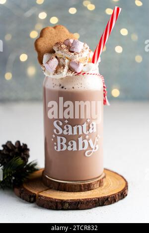 Heiße Schokolade mit Schlagsahne serviert mit Zuckerrohr, Marshmallows und Lebkuchenstern, Vorderansicht. Stockfoto