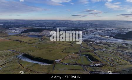 Aus einem Flugzeug aus der Vogelperspektive auf die Landschaft und die lebhafte grüne Landschaft darunter, gespickt mit kleinen Häusern und gewundenen Straßen Stockfoto