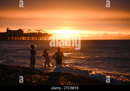 Brighton Großbritannien 14. Dezember 2023 - Schwimmer am frühen Morgen fangen den Sonnenaufgang in Brighton an einem kühlen Morgen entlang der Südküste an . Die Schwimmer sind Mitglieder von iSWIM, einer Gemeinschaft von Schwimmern mit Sitz in Brighton & Hove, die mit dem Brighton Sailing Club verbunden ist: Credit Simon Dack / Alamy Live News Stockfoto