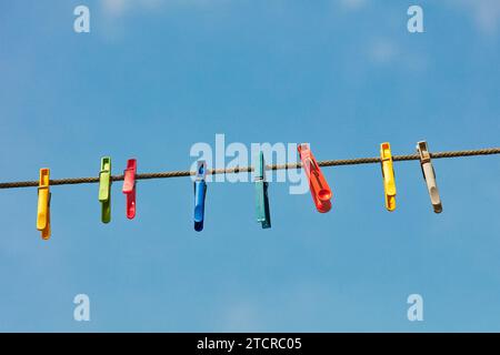 Bunte Plastiklappen auf einer Wäscheleine vor klarem blauem Himmel. Stockfoto