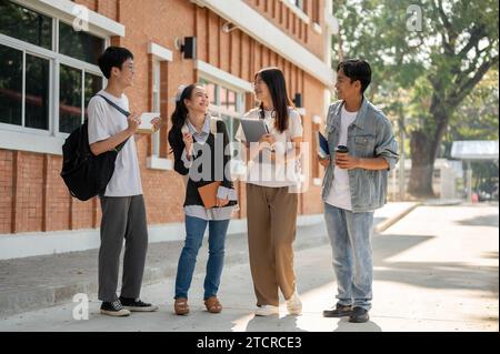 Eine Gruppe von verschiedenen glücklichen asiatischen Studenten spricht gern, teilt Ideen und plaudert nach dem Unterricht auf einem Fußweg auf ihrem Campus. Freundschaft und Stockfoto