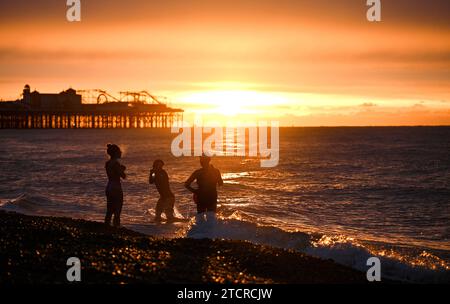 Brighton Großbritannien 14. Dezember 2023 - Schwimmer am frühen Morgen fangen den Sonnenaufgang in Brighton an einem kühlen Morgen entlang der Südküste an . Die Schwimmer sind Mitglieder von iSWIM, einer Gemeinschaft von Schwimmern mit Sitz in Brighton & Hove, die mit dem Brighton Sailing Club verbunden ist: Credit Simon Dack / Alamy Live News Stockfoto