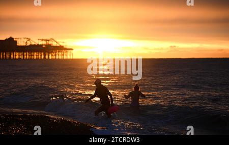 Brighton Großbritannien 14. Dezember 2023 - Schwimmer am frühen Morgen fangen den Sonnenaufgang in Brighton an einem kühlen Morgen entlang der Südküste an . Die Schwimmer sind Mitglieder von iSWIM, einer Gemeinschaft von Schwimmern mit Sitz in Brighton & Hove, die mit dem Brighton Sailing Club verbunden ist: Credit Simon Dack / Alamy Live News Stockfoto