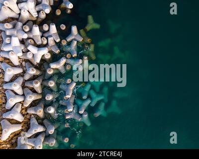 Drohnenansicht eines Wellenbrechers aus der Luft. Wellenbrecher im Meer, eine Ansammlung von Beton-Tetrapodenbrechern. Stockfoto