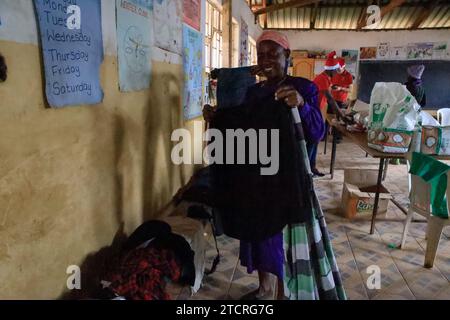 NAIROBI, Afrika. Dezember 2023. Frauen, die Weihnachtskleidung überprüfen, verteilt von Family Care Mission in der orthodoxen katholischen Kirche in Nairobi, Kenia. Die Einwohner von Kibera Slum erhielten Weihnachtsgeschenke von Family Care Missions (einer seit 2001 registrierten Wohltätigkeitsorganisation in Kenia, die sich aus voll- und Teilzeit-Freiwilligen zusammensetzt, die ihre Zeit und ihre Anstrengungen für die Unterstützung von Unterprivilegierten und Benachteiligten der Gesellschaft widmen. Ihre Freiwilligen suchen lohnende Projekte aus, um das Bewusstsein für die „Ärmsten der Armen“ zu schärfen und sie zu unterstützen. FCM bietet Dienstleistungen wie die Beschaffung von Mitteln für Schulessen, Stockfoto