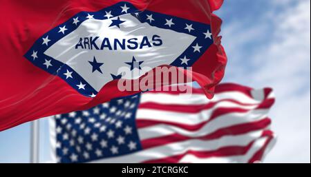 Nahaufnahme der Flagge von Arkansas, die an einem klaren Tag mit der amerikanischen Flagge winkt. 3D-Illustration Redner. Selektiver Fokus. Gewelltes Material Stockfoto