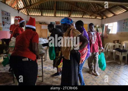 NAIROBI, Afrika. Dezember 2023. Frauen, die Chrismas-Nahrungsmittel erhalten, verteilt von Freiwilligen der Family Care Mission in der Orthodoxen Kirche in Kibera, Nairobi. Die Einwohner von Kibera Slum erhielten Weihnachtsgeschenke von Family Care Missions (einer seit 2001 registrierten Wohltätigkeitsorganisation in Kenia, die sich aus voll- und Teilzeit-Freiwilligen zusammensetzt, die ihre Zeit und ihre Anstrengungen für die Unterstützung von Unterprivilegierten und Benachteiligten der Gesellschaft widmen. Ihre Freiwilligen suchen lohnende Projekte aus, um das Bewusstsein für die „Ärmsten der Armen“ zu schärfen und sie zu unterstützen. FCM bietet Dienstleistungen wie die Beschaffung von Finanzmitteln für die lun der Schule an Stockfoto