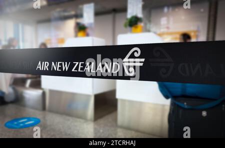 Auckland, NZ, 4. Dezember 2023: Ein Air New Zealand-Band hebt sich an einem geschäftigen Flughafenschalter hervor und deutet auf die Spannung der bevorstehenden Reisen hin Stockfoto