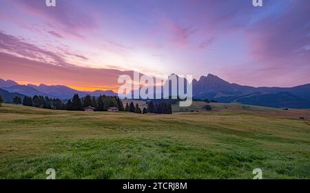 Seiser Alm, Italien, UNESCO-Weltkulturerbe, lebendige Wiesen, urige Hütten. Charmante Almhäuser inmitten üppiger Weiden umrahmen die majestätische Kulisse der Alpe Stockfoto