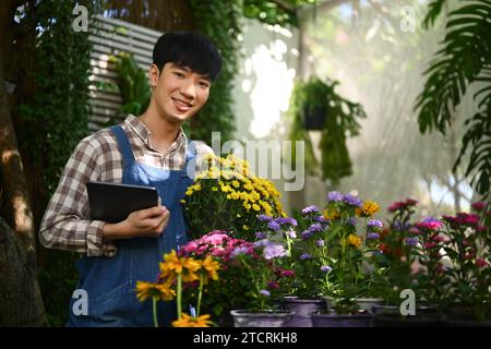 Hübscher asiatischer Blumenhändler mit frischen Blumen in seinem Blumenladen Stockfoto