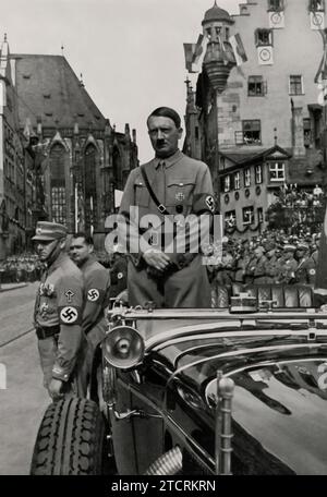 Bei der „Rally of Freedom“ wird Adolf Hitler in seinem Auto gefangen genommen und wartet auf die Ankunft der braunen Säulen, der uniformierten Reihen der SA (Sturmabteilung) und anderer NSDAP-Formationen. Dieses Bild, in dem Hitler über die Massen erhoben wurde, unterstreicht seine dominante Stellung innerhalb der Partei. Die disziplinierten Reihen von SA-Mitgliedern, bekannt für ihre braunen Uniformen, symbolisieren den Fokus der Partei auf militaristische Ordnung und Einheit. Dieser Moment verdeutlicht den orchestrierten Charakter der Nazi-Kundgebungen, bei denen Massenversammlungen und Loyalitätsbekundungen für die Stärkung der Ideologie des Regimes von zentraler Bedeutung waren. Stockfoto