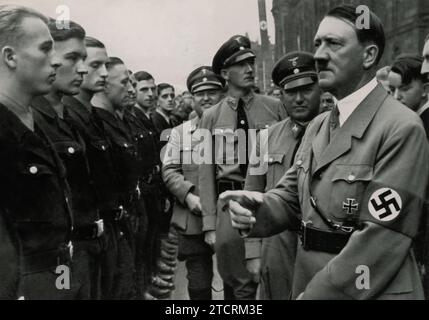 Beim Reichsparteitag 1935 werden Adolf Hitler und Dr. Robert Ley zusammen mit Arbeitseinheiten gesehen. Dieses Treffen bei der NSDAP-Kundgebung in Nürnberg unterstreicht den Fokus des Regimes auf organisierte Arbeit und ihre Integration in die NS-Ideologie. Ley, Chef der Deutschen Arbeitsfront, zeigt neben Hitler, das Engagement des Regimes für die Mobilisierung und Vereinigung der Arbeitskräfte zur Unterstützung seiner Politik. Stockfoto