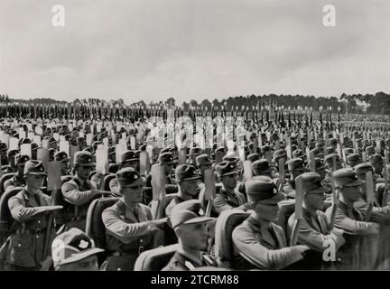 In diesem Bild werden die Arbeitssoldaten auf einer Kundgebung der NSDAP gezeigt, die den Reichsarbeitsdienst (Rad) repräsentiert, einen wichtigen Bestandteil der Arbeitskräfte des Regimes. Diese Soldaten, integraler Bestandteil der NS-Vision einer disziplinierten und fleißigen Gesellschaft, werden hier als Teil des Reichsparteitages 1935 in Nürnberg gesehen. Ihre Präsenz unterstreicht die Betonung des Regimes auf organisierte Arbeit als Symbol nationaler Stärke und Einheit und steht im Einklang mit der breiteren Propagandaerzählung eines wiederbelebten Deutschlands. Stockfoto