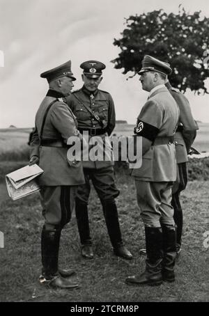 Adolf Hitler, zusammen mit Reichskriegsminister General Werner von Blomberg und Oberbefehlshaber der Armee, General Werner von Fritsch, 1935 bei den Militärmanövern auf dem Münsterlager-Trainingsgelände. Dieses Bild ist ein bedeutendes Bild von Hitlers direkter Beteiligung an militärischen Angelegenheiten und unterstreicht die Präsenz dieser wichtigen militärischen Führer. Die Veranstaltung unterstreicht den Fokus des NS-Regimes auf militärische Expansion und Bereitschaft, wobei von Blomberg und von Fritsch die strategische Planung und Führung hervorhoben, die die militärischen Fortschritte Deutschlands zu dieser Zeit vorangetrieben haben. Stockfoto