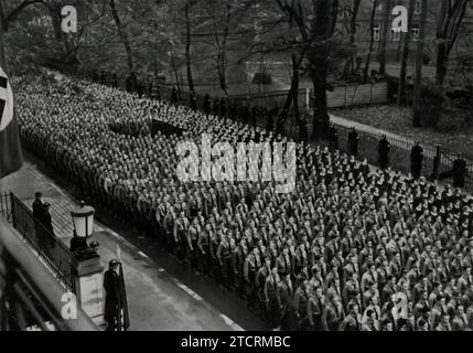 Am 9. November 1935 versammeln sich in München Mitglieder der Hitlerjugend vor dem braunen Haus, dem Hauptquartier der NSDAP, bevor sie formell in die Partei eingezogen werden. Dieses Bild fängt einen wichtigen Moment im Prozess der Jugendindoktrinierung des NS-Regimes ein und unterstreicht die Bedeutung, die der Integration junger Menschen in die Parteistruktur beigemessen wird. Die Zeremonie, die an einem symbolischen Ort stattfindet, unterstreicht das Engagement des Regimes, die Loyalität der nächsten Generation zu gestalten und zu sichern. Stockfoto