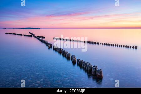 Hölzerne Wellenbrecher, die in Richtung Sonnenuntergang in Dranske, Rügen, Deutschland zeigen. Hochwertige Fotos Stockfoto