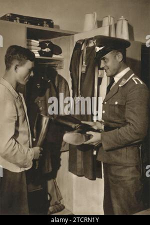 Auf dem Foto wird ein deutscher Offizier bei der Inspektion eines Schließfachs gesehen, der wahrscheinlich einem Rekruten der Luftwaffe gehört. Diese Praxis der Schließfachinspektionen war ein routinemäßiger, aber wichtiger Aspekt des militärischen Lebens, der dazu diente, Disziplin und Ordnung in den Reihen zu stärken. In der Luftwaffe, wo Präzision und Akribie besonders geschätzt wurden, stellten solche Inspektionen sicher, dass persönliche und ausgestellte Geräte in optimalem Zustand und einsatzbereit gehalten wurden. Stockfoto