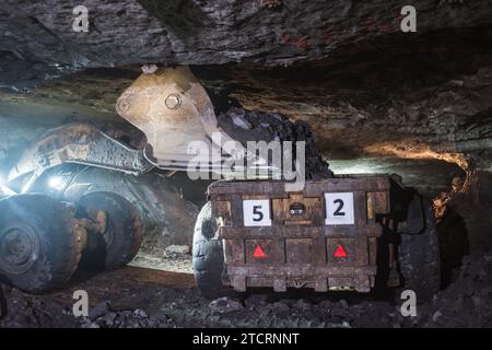 Der Lader gießt Kupfererz auf einen Lkw in der Mine Stockfoto