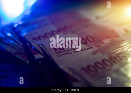 Ein Stapel gefalteter hunderttausend Rupien Banknoten indonesisches Geld selektiver Fokus Dunkelblau Beleuchtung Stockfoto