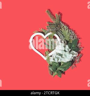 Kreatives Layout mit immergrünen Zweigen und Herzform. Jubiläum- und Valentinstag-Konzept. Flache Lagen. Stockfoto
