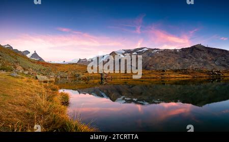 Heller, malerischer Herbstblick mit einem wunderschönen See und schneebedeckten Bergen und dem Wald und ihren Reflexionen vor dem Hintergrund des Himmels und des Clou Stockfoto