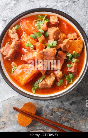 Chinesisches indonesisches Babi Tomat Schweinefleisch gedünstete Tomaten in einer Schüssel auf dem Tisch. Vertikale Draufsicht von oben Stockfoto