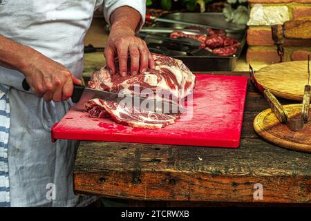 In einer Außenküche bereitet ein Koch Fleisch zu, um gegrillte Braten zu machen. Abruzzen, Italien. Europa Stockfoto