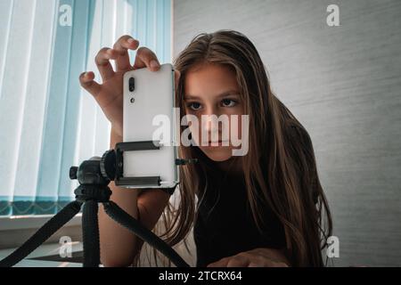 Teenager-Mädchen filmt ein Video von sich selbst auf dem Handy. Das Mädchen trägt sich vor die Kamera und nimmt die Geschichten auf. Stockfoto
