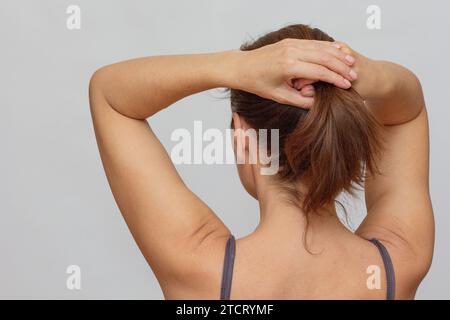 Der Rücken einer Frau, die Haare hält Stockfoto