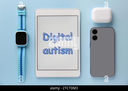 Tablet mit Phrase Digital Autism und Geräten auf hellblauem Hintergrund, flach gelegt. Suchtverhalten Stockfoto