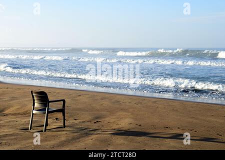 Leerer Stuhl am natürlichen mediterranen Sandstrand mit Blick auf das Meer an einem wunderschönen Herbsttag, Halbinsel Peloponnes, Griechenland, Europa Stockfoto