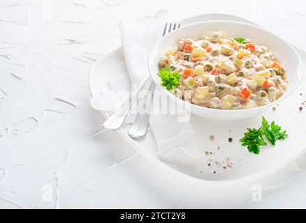 Teller mit russischem Salat oder französischem Salat mit Gemüse und Ei mit Mayonnaise auf einem weißen Tisch Stockfoto