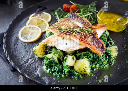Fischgericht: Gebratenes Seebarschfilet und gekochte Mangold mit Kartoffeln, Knoblauch und Olivenöl. Mediterranes gesundes Essen mit Filet Stockfoto