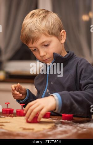 7-jähriger Junge, der Weihnachtsbrötchen zubereitet. Stockfoto