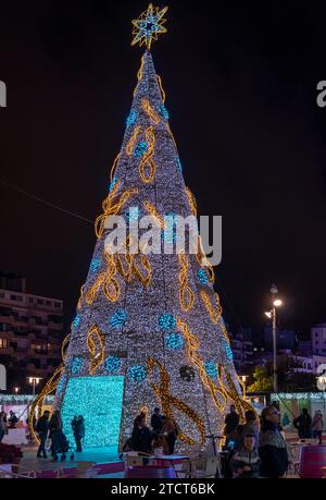 Palma de Mallorca, Spanien; 12. dezember 2023: Weihnachtsmarkt mit Kunden und einem großen Weihnachtsbaum, der nachts beleuchtet wird. Palma de Mallorca, Stockfoto