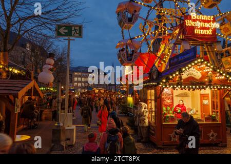 Bonn, Deutschland - 6. Dezember 2023: Dämmerungsblick auf ein großes Notausgangsschild auf einem belebten Weihnachtsmarkt mit festlichen Lichtern und Dekorationen, Besucher Stockfoto