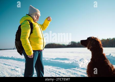 Ältere Frau aus den 60er Jahren, die auf dem Hügel relaxt. Frau trinkt heißen Tee aus der Thermotasse und genießt den Panoramablick auf den Stadtpark. Stockfoto