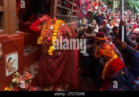 Dhading, Bagmati, Nepal. Dezember 2023. Ein Gläubiger mit der Göttin betritt den Tempel während der Feier des Tripurasundari-Festivals in Dhading, Nepal am 14. Dezember 2023. Gläubige tragen die Göttin Tripurasundari Bhagwati während des Festivals vom Tempel des Salyankot zum Tempel hinunter im Salyanbesi-Tal am Ufer des Netrawati-Flusses. Die Göttin Tripurasundari Bhagwati reist jährlich in drei verschiedenen Tempeln, um religistische Rituale durchzuführen. Quelle: ZUMA Press, Inc./Alamy Live News Stockfoto